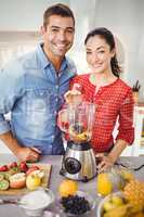 Portrait of smiling couple preparing fruit juice