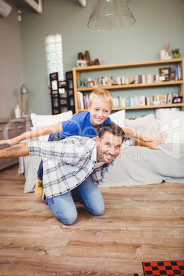 Cheerful father and son playing on hardwood floor