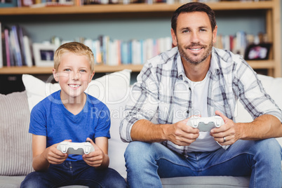 Portrait of smiling father and son playing video game
