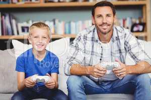 Portrait of smiling father and son playing video game