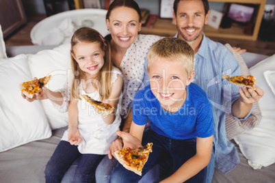 Portrait of smiling family holding pizza slices while sitting on