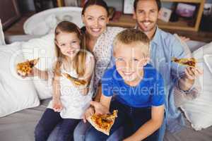Portrait of smiling family holding pizza slices while sitting on
