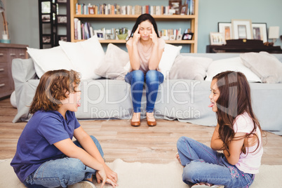 Children playing while mother sitting on sofa