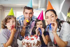 Happy family blowing party horn during birthday celebration