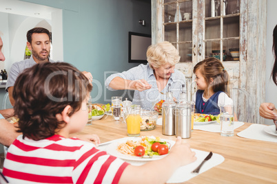 Smiling family with grandparents sitting at dining table