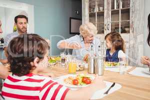 Smiling family with grandparents sitting at dining table