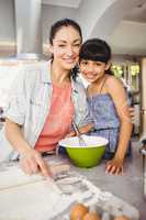 Portrait of cheerful woman preparing food with daughter