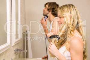 Cute couple using a razor and a straightener