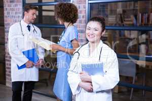 Female doctor standing near library with digital tablet