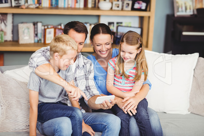 Family using mobile phone while sitting on sofa
