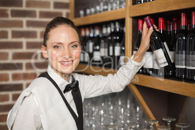 Barmaid taking bottle out of shelf