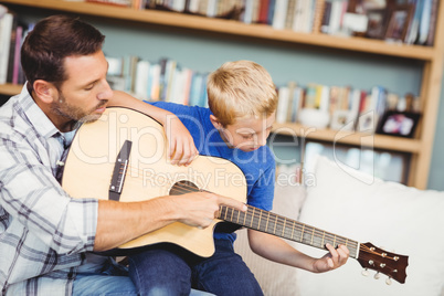 Father teaching son to play guitar