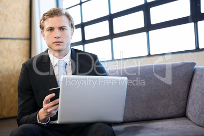 Businessman using laptop and mobile phone