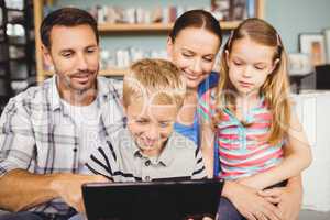 Family smiling while using technologies on sofa at home