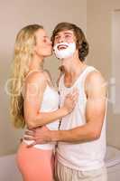 Blonde kissing her boyfriend with shaving foam on the face