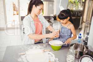 Woman preparing food with daughter at home
