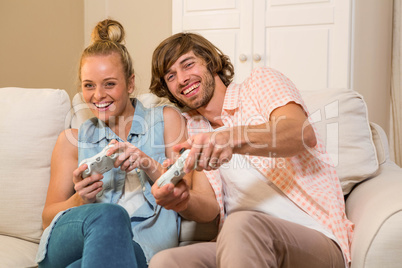 Cute couple playing video games sitting on the couch