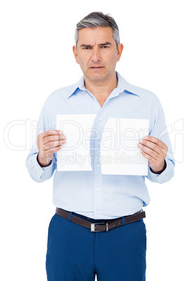 Stern man holding ripped paper