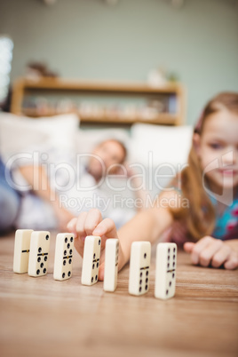 Girl arranging domino on hardwood floor at home