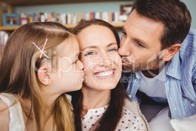 Close-up of father and daughter kissing mother