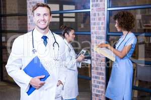 Male doctor standing near library with clipboard