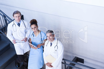 Portrait of doctors standing on staircase with document