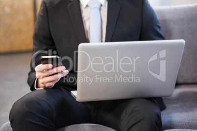 Businessman using laptop and mobile phone