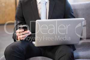 Businessman using laptop and mobile phone