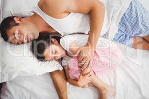 Father sleeping with daughter on bed at home