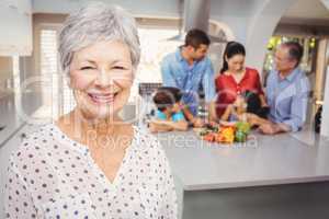 Close-up of senior woman with family preparing food in backgroun