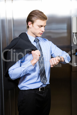 Businessman checking time while waiting for elevator