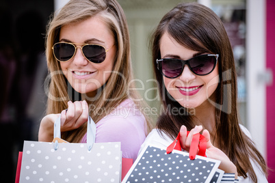 Portrait of beautiful women in sunglasses holding shopping bags