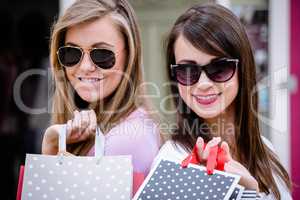 Portrait of beautiful women in sunglasses holding shopping bags