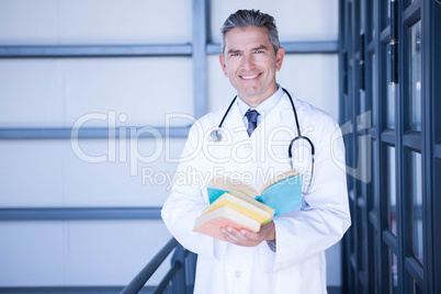 Portrait of male doctor standing with medical book Portrait of male doctor standing with medical book