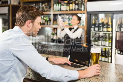 Man working on laptop with beer in hand