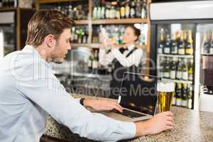 Man working on laptop with beer in hand