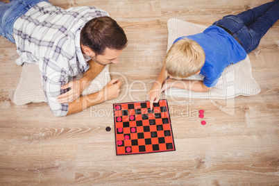 Father and son playing checker game while at home