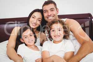 Cheerful family lying on bed against wall at home