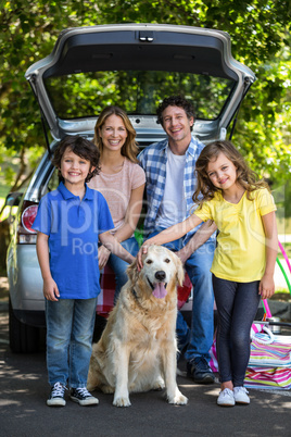 Smiling family in front of a car