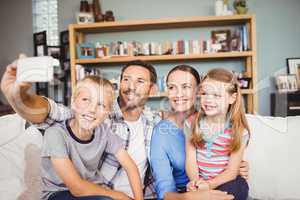 Family taking selfie with mobile phone on sofa at home