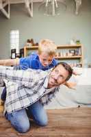 Happy father playing with son on hardwood floor