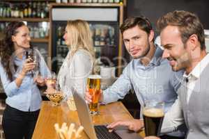 Men working on laptop while women talk behind