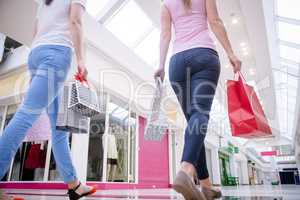 Rear view of women walking in mall with shopping bags