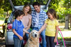 Smiling family in front of a car
