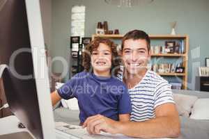 Portrait of cheerful father and son using computer