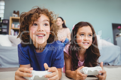 Close-up of happy siblings with controllers playing video game