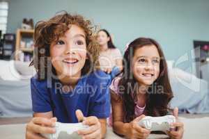 Close-up of happy siblings with controllers playing video game