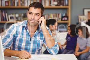 Confident man using mobile phone while family in background