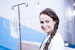 Portrait of female doctor carrying saline stand