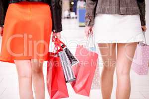 Rear view of women walking in mall with shopping bags
